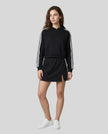 Full body front view of the Athlesi TrackLine Slit Skirt in black styled with the TrackLine Cropped Hoodie
