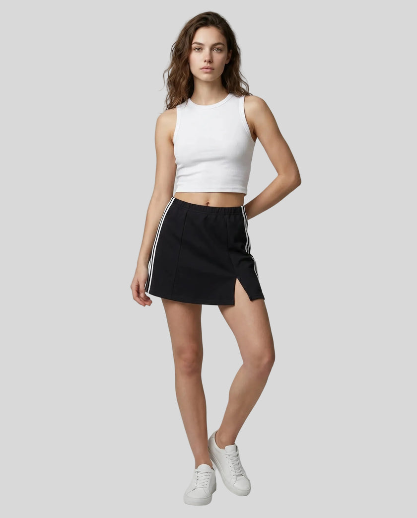 Full body front view of the Athlesi TrackLine Slit Skirt in black styled with a white cropped tank top