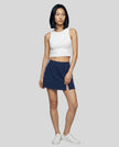 Full body front view of the Athlesi TrackLine Slit Skirt in blue styled with a white cropped tank top