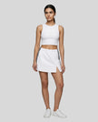 Full body front view of the Athlesi TrackLine Slit Skirt in white styled with a white cropped tank top