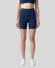 Model wearing the TrackLine Sprint Shorts in navy blue with pink and white side stripes front view