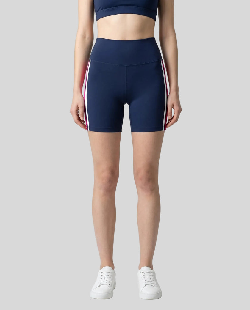 Model wearing the TrackLine Sprint Shorts in navy blue with pink and white side stripes front view