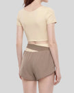 Woman wearing TrackLine Synergy Cropped Tee in Apricot with Khaki panel, mid body back angle view