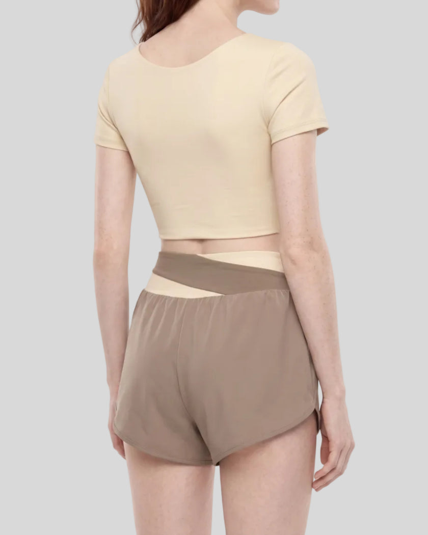 Woman wearing TrackLine Synergy Cropped Tee in Apricot with Khaki panel, mid body back angle view