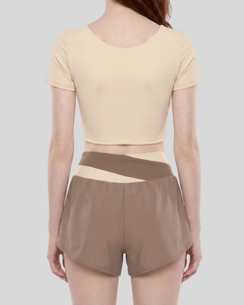 Woman wearing TrackLine Synergy Cropped Tee in Apricot with Khaki panel, mid body back view