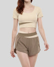 Woman wearing TrackLine Synergy Cropped Tee in Apricot with Khaki panel, mid body front angle view