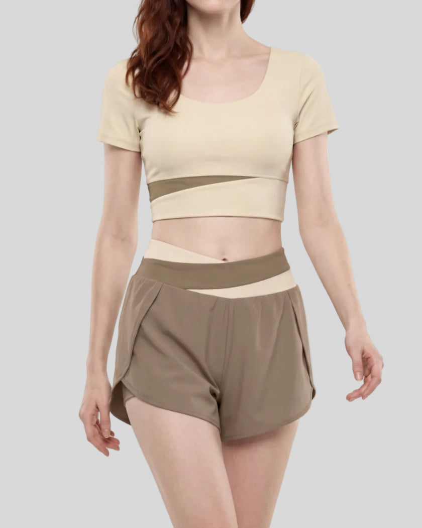 Woman wearing TrackLine Synergy Cropped Tee in Apricot with Khaki panel, mid body front angle view