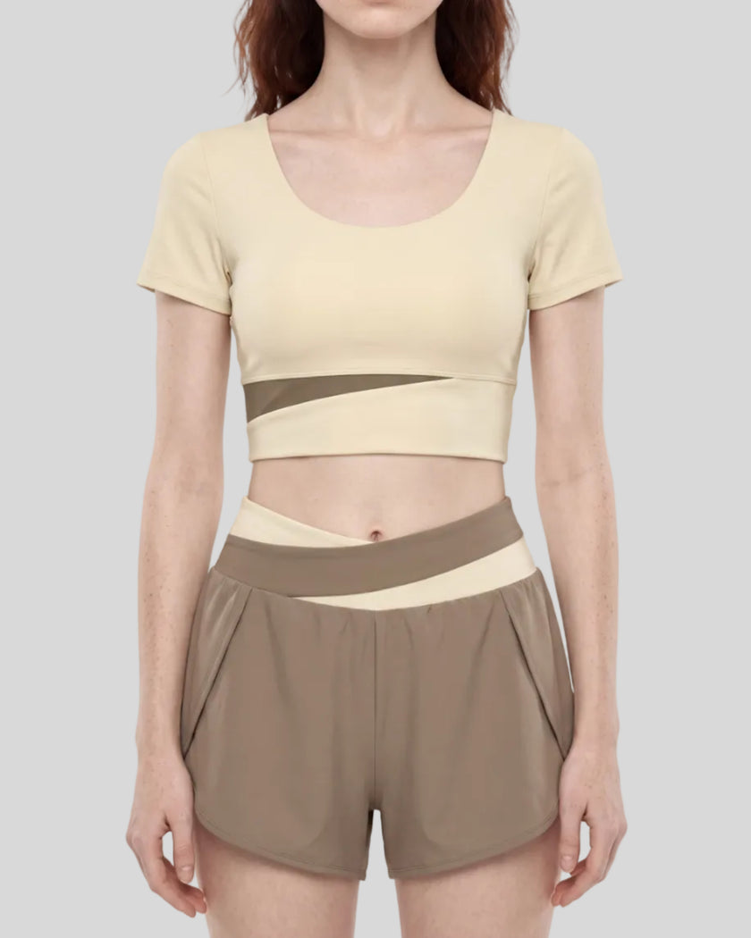 Woman wearing TrackLine Synergy Cropped Tee in Apricot with Khaki panel, mid body front view