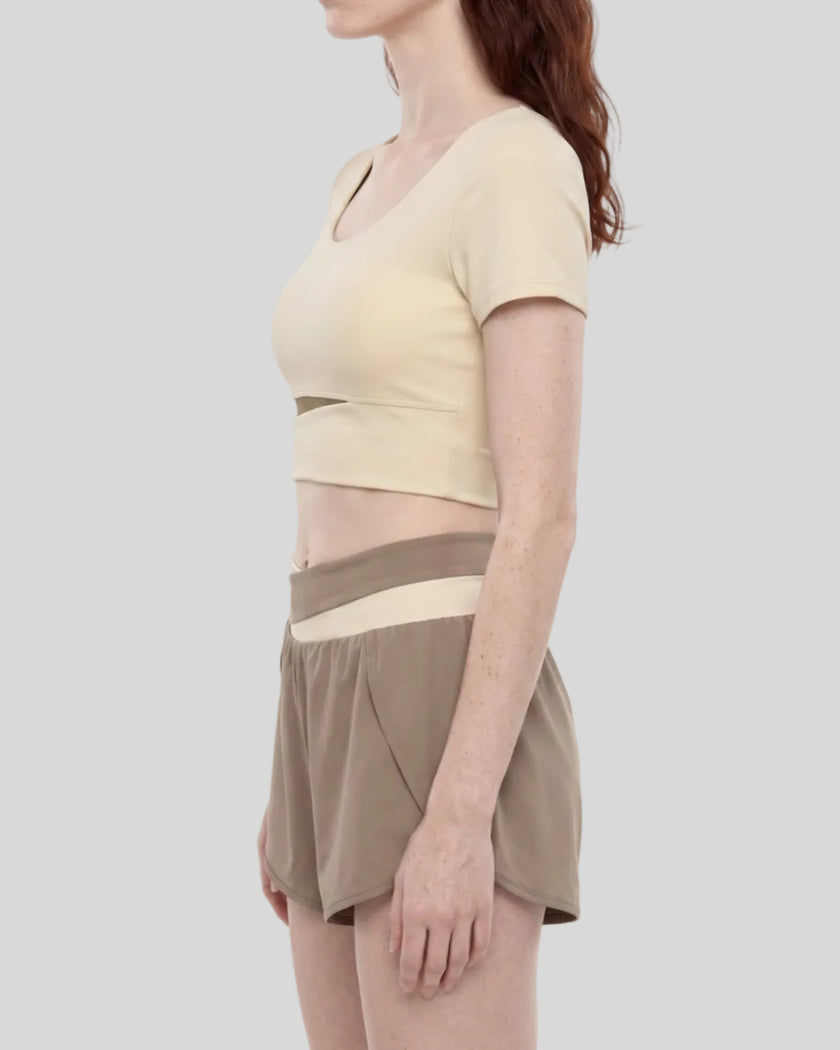 Woman wearing TrackLine Synergy Cropped Tee in Apricot with Khaki panel, mid body side view