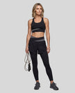 Full body front view of woman wearing TrackLine Synergy Layered Leggings in black and dark gray