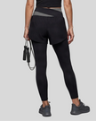 Lower body back view of woman wearing TrackLine Synergy Layered Leggings in black with dark gray crossover waistband