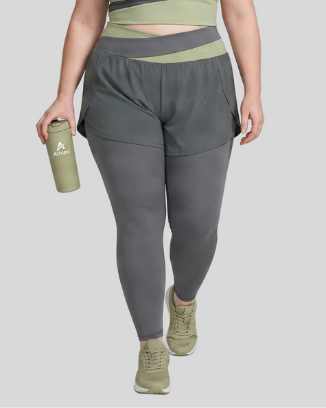Lower body front view of woman wearing TrackLine Synergy Layered Leggings in dark gray with bean green crossover waistband