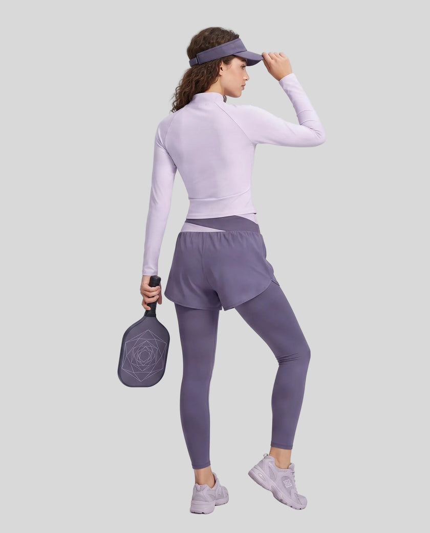 Full body back view of woman wearing TrackLine Synergy Layered Leggings in deep purple and light purple
