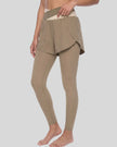Lower body front angled view of woman wearing TrackLine Synergy Layered Leggings in light coffee with apricot crossover waistband