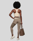 Full body back view of woman wearing TrackLine Synergy Layered Leggings in light coffee and apricot