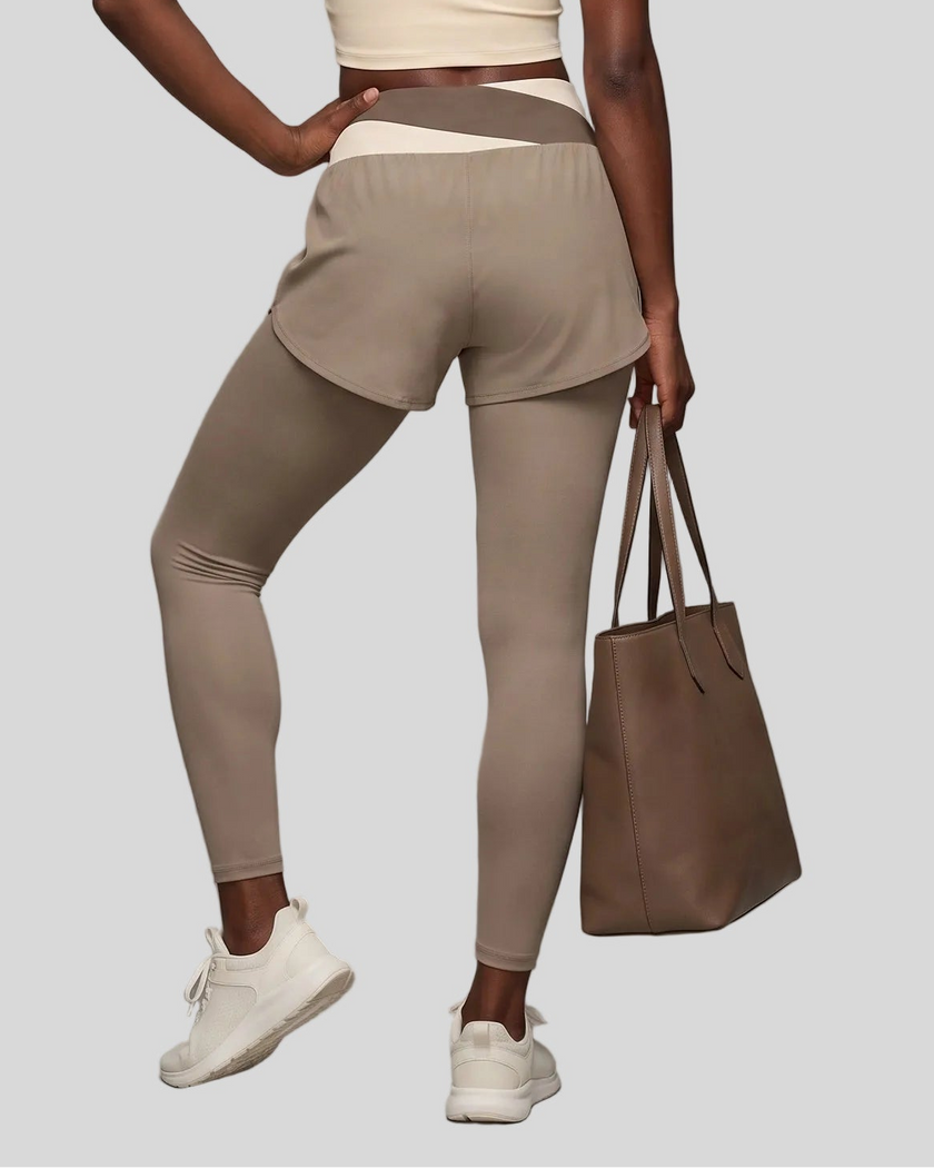 Lower body back view of woman wearing TrackLine Synergy Layered Leggings in light coffee with apricot crossover waistband