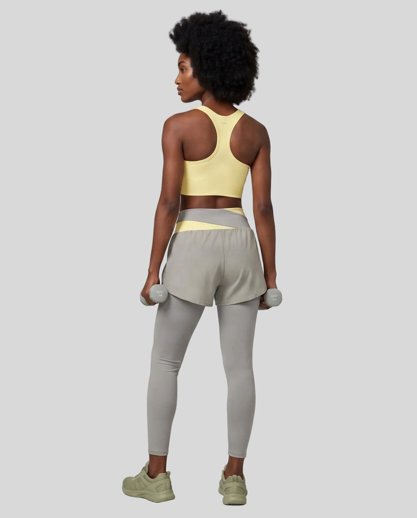 Full body back view of woman wearing TrackLine Synergy Layered Leggings in light gray and light yellow