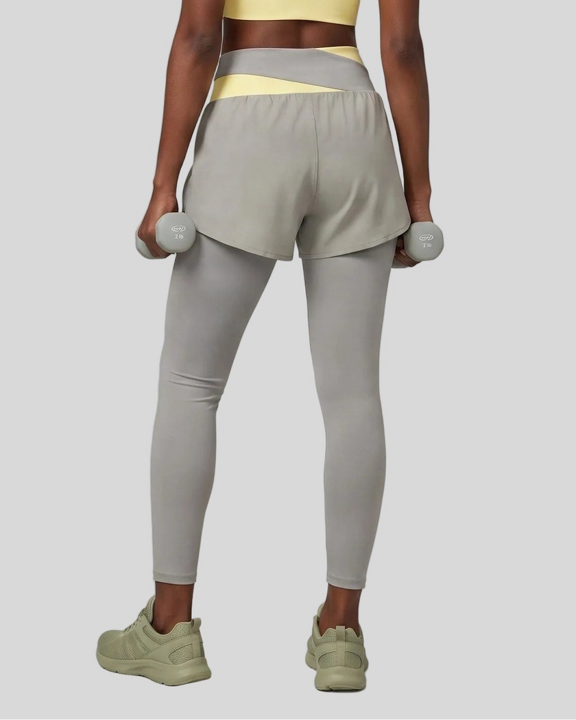Lower body back view of woman wearing TrackLine Synergy Layered Leggings in light gray with light yellow crossover waistband