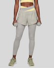 Lower body front view of woman wearing TrackLine Synergy Layered Leggings in light gray with light yellow crossover waistband