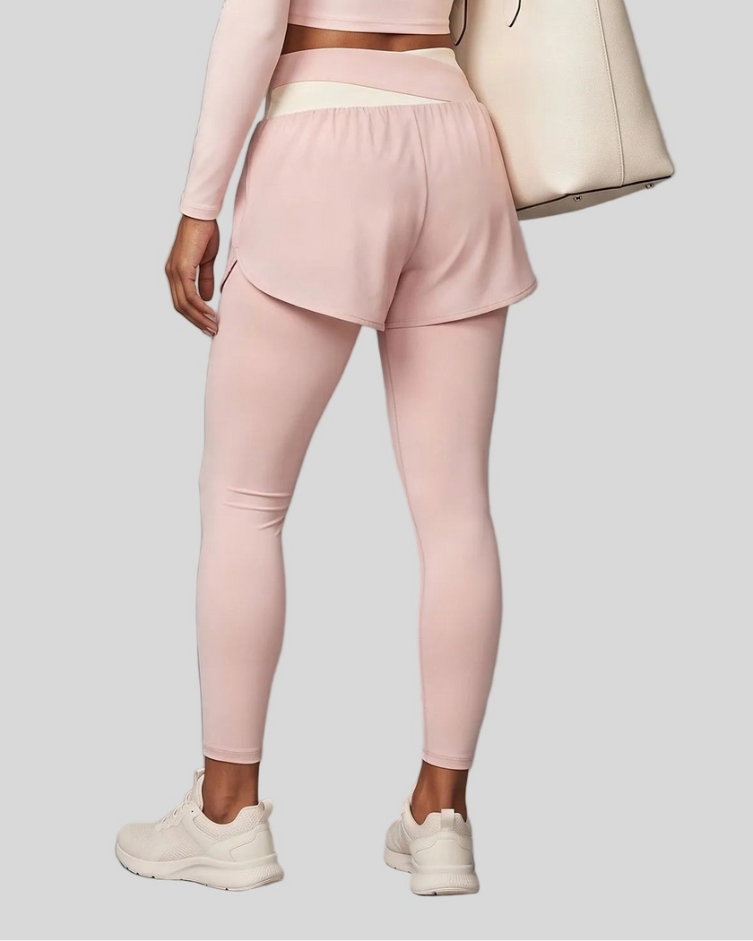 Lower body back view of woman wearing TrackLine Synergy Layered Leggings in light pink with apricot crossover waistband