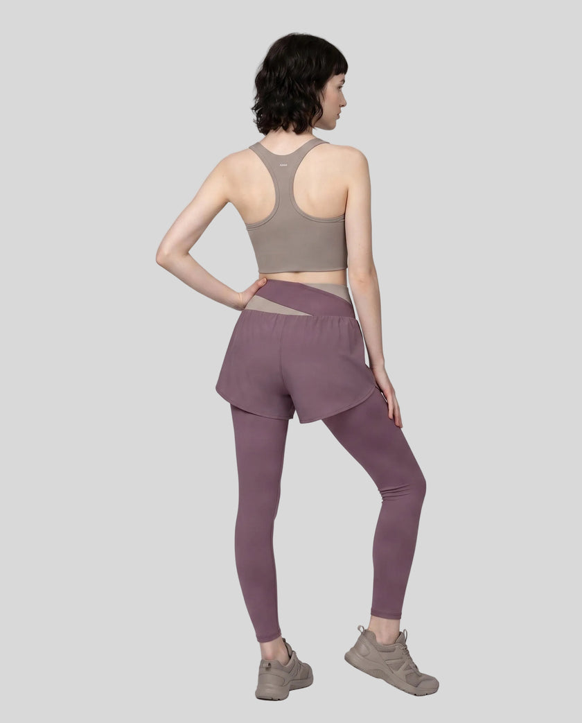 Full body back view of woman wearing TrackLine Synergy Layered Leggings in misty purple and gray purple