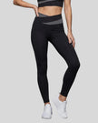 Woman wearing TrackLine Synergy Leggings in Black with Dark Gray crossover waistband, lower body front view