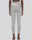 Woman wearing TrackLine Synergy Leggings in Light Gray with Light Blue crossover waistband, lower body back view