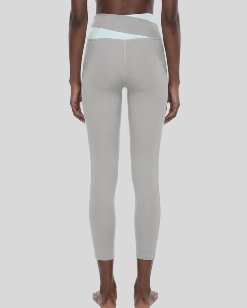 Woman wearing TrackLine Synergy Leggings in Light Gray with Light Blue crossover waistband, lower body back view