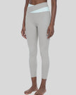 Woman wearing TrackLine Synergy Leggings in Light Gray with Light Blue crossover waistband, lower body front angle view