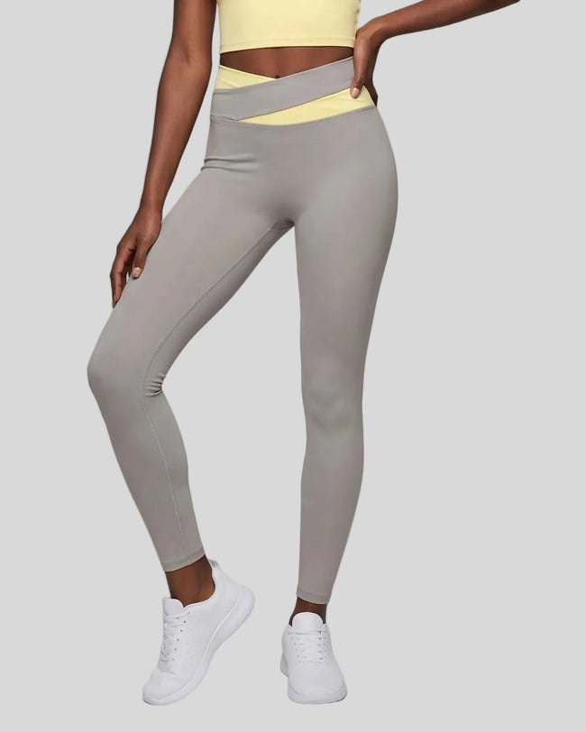 Woman wearing TrackLine Synergy Leggings in Light Gray with Light Yellow crossover waistband, lower body front view