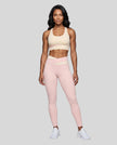 Woman wearing TrackLine Synergy Leggings in Light Pink with Apricot crossover waistband, full body front view