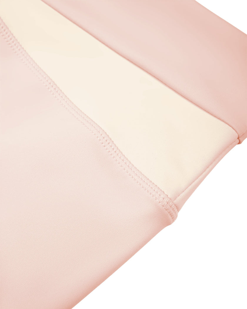 Side close-up of crossover color-block waistband construction on TrackLine Synergy Leggings in Light Pink and Apricot