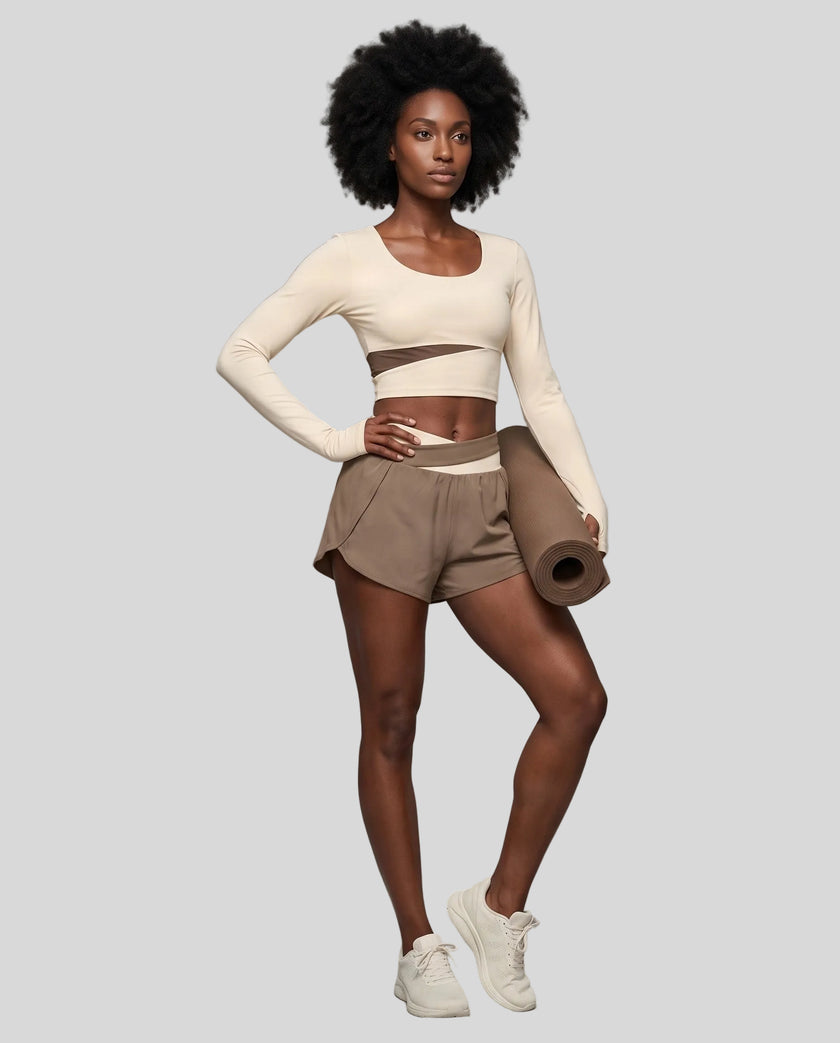 Full body view of woman wearing TrackLine Synergy Long Sleeve Top in apricot with khaki color-block detail