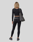 Full body back view of woman wearing TrackLine Synergy Long Sleeve Top in black