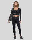 Full body view of woman wearing TrackLine Synergy Long Sleeve Top in black with dark gray color-block detail