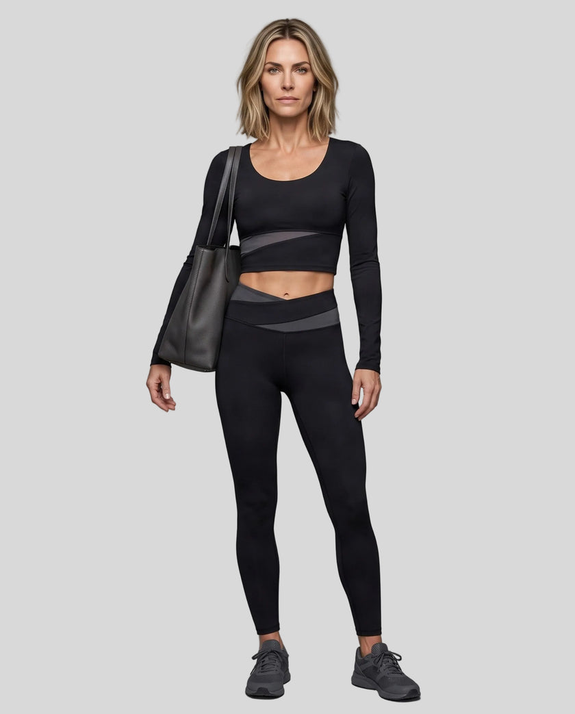 Full body view of woman wearing TrackLine Synergy Long Sleeve Top in black with dark gray color-block detail