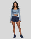 Full body view of woman wearing TrackLine Synergy Long Sleeve Top in gray blue with navy blue color-block detail