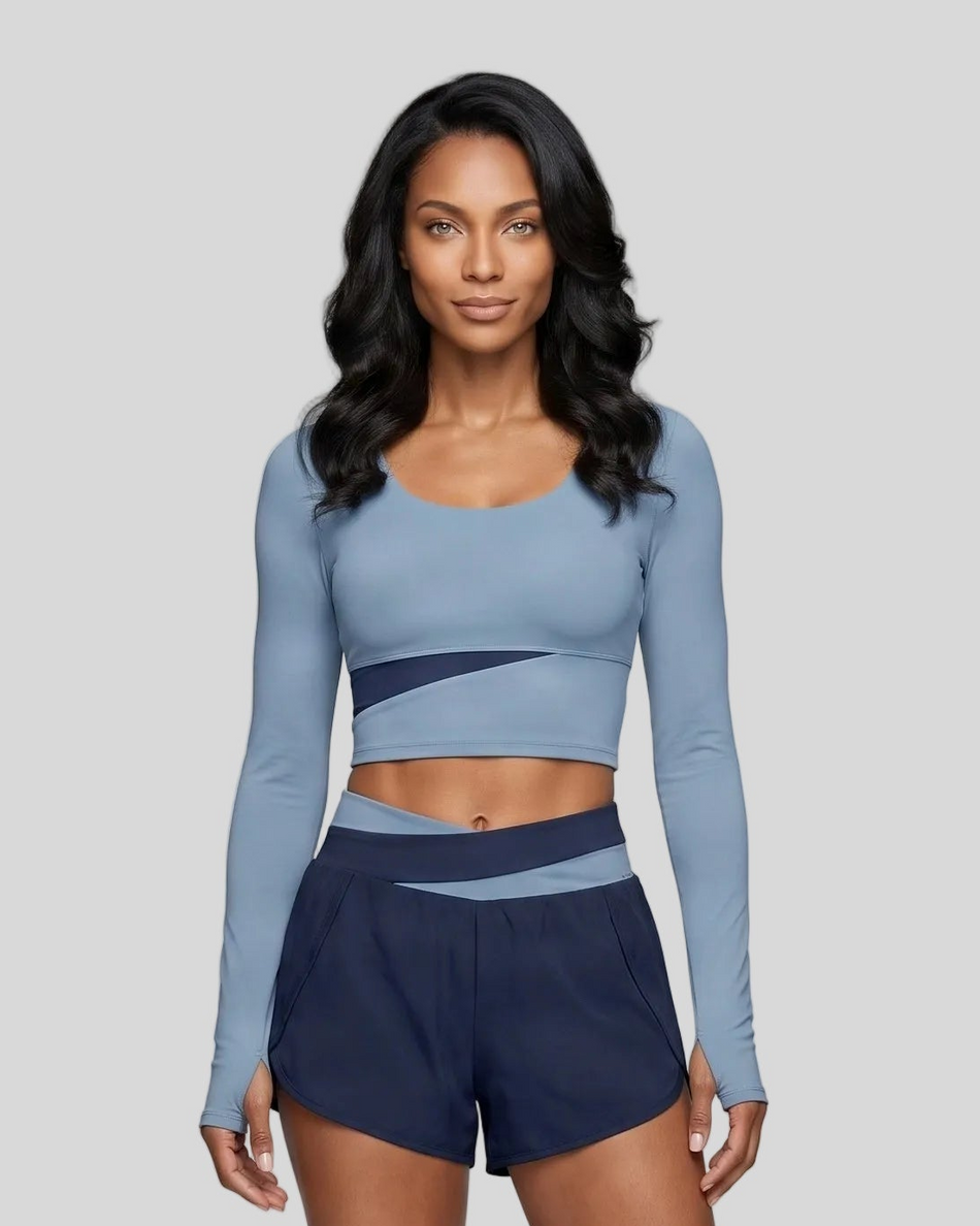 Woman wearing TrackLine Synergy Long Sleeve Top in gray blue with navy blue asymmetric front detail