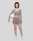 Full body view of woman wearing TrackLine Synergy Long Sleeve Top in gray purple with misty purple color-block detail