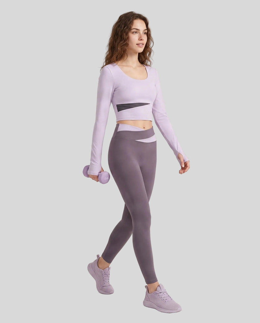Full body view of woman wearing TrackLine Synergy Long Sleeve Top in light purple with deep purple color-block detail