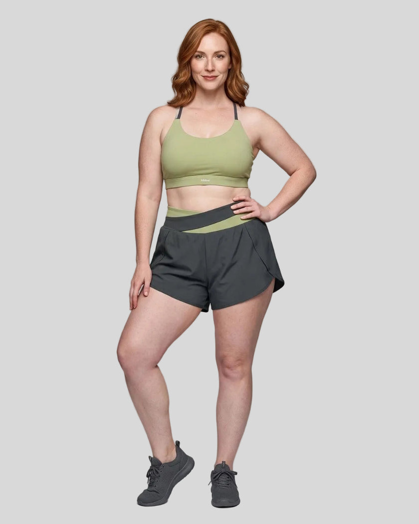 Woman wearing TrackLine Synergy Performance Shorts in Dark Gray with Bean Green waistband, front view
