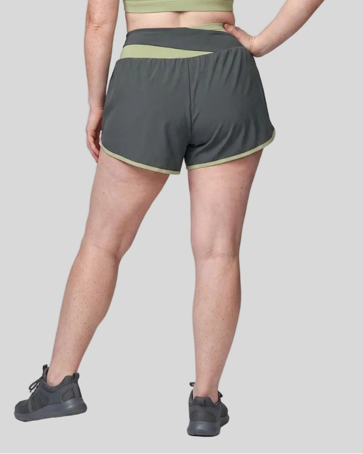 Woman wearing TrackLine Synergy Performance Shorts in Dark Gray with Bean Green waistband, lower body back view