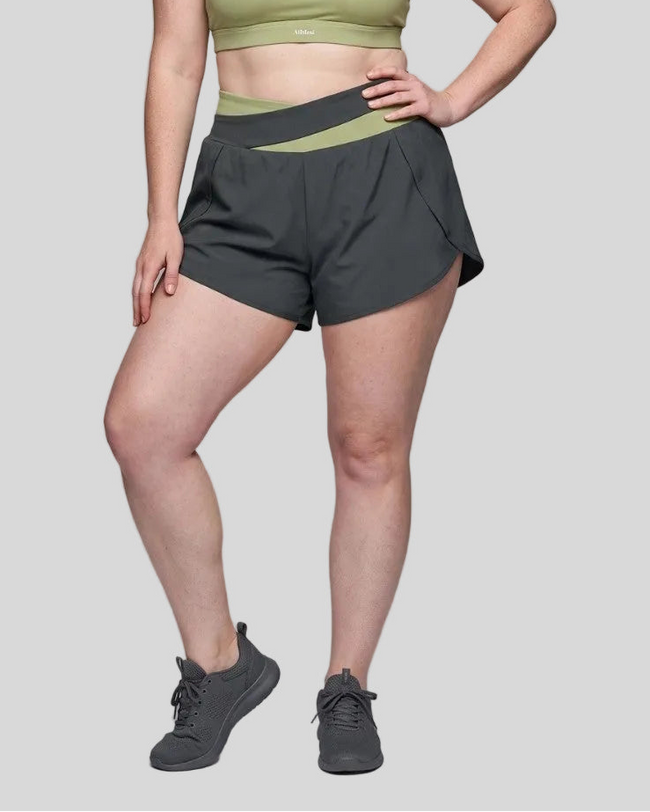 Woman wearing TrackLine Synergy Performance Shorts in Dark Gray with Bean Green waistband, lower body front view