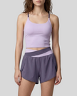 A woman modeling a deep purple and light purple TrackLine Synergy Performance Shorts with a matching tank top.
