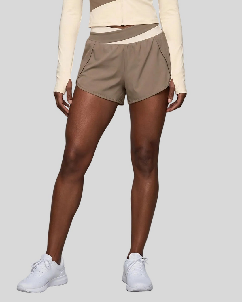 Lower body view of woman modeling a light coffee and apricot TrackLine Synergy Performance Shorts with a matching sports jacket.