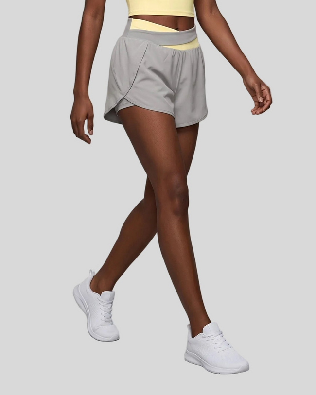 Woman wearing TrackLine Synergy Performance Shorts in Light Gray with Light Yellow waistband, lower body front angle view