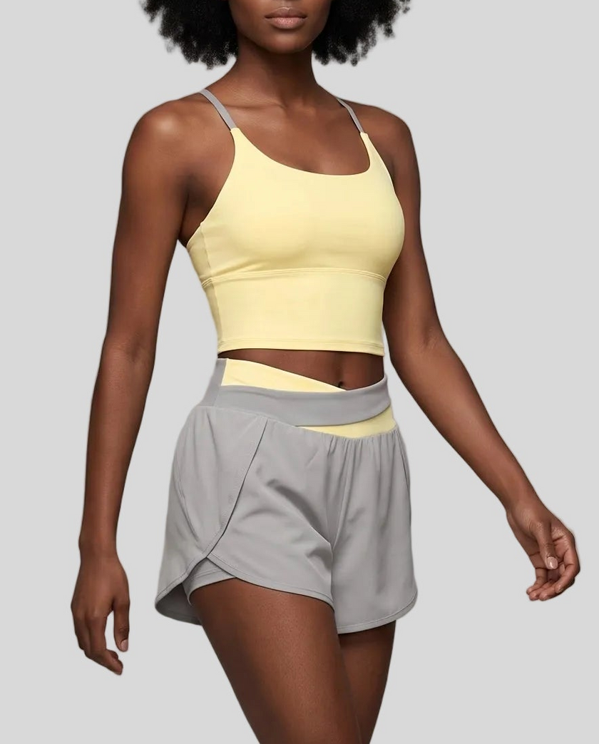 A woman modeling a light gray and light blue TrackLine Synergy Performance Shorts with a matching tank top.
