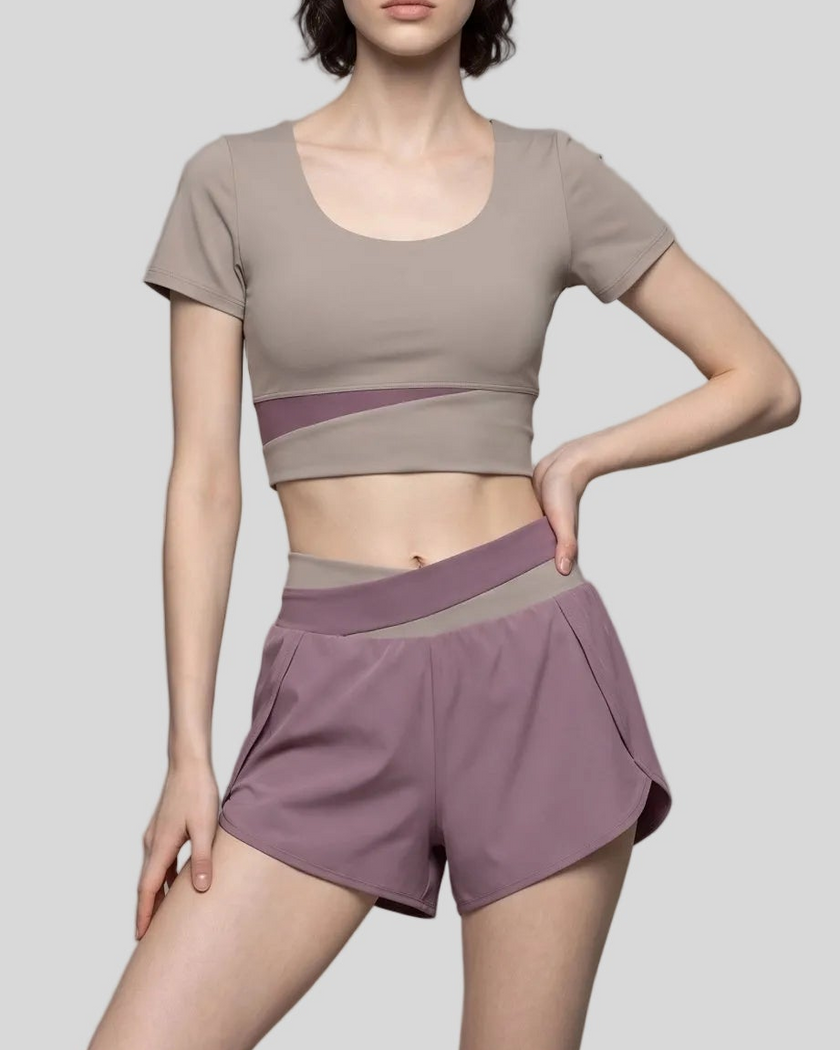 A woman modeling a misty purple and gray purple TrackLine Synergy Performance Shorts with a matching sports bra.