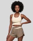 Woman wearing TrackLine Synergy Racerback Sports Bra in Apricot with Khaki detail, front view