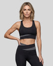 Woman wearing TrackLine Synergy Racerback Sports Bra in Black with Dark Gray detail, front view